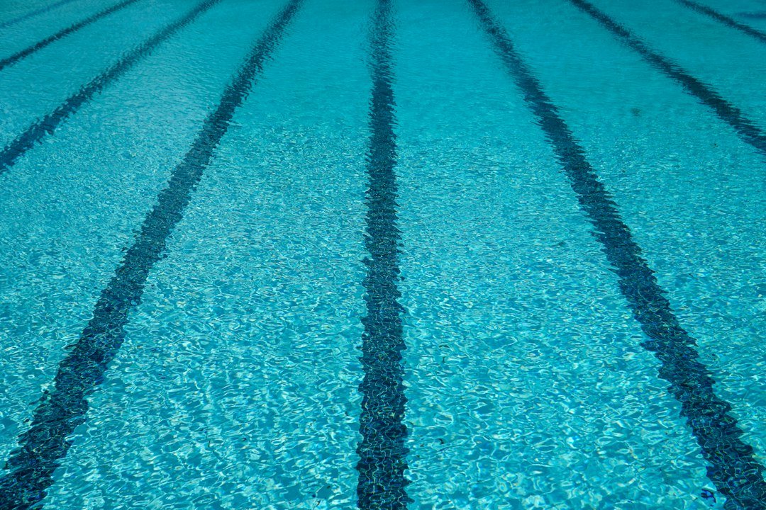Clear blue swimming pool water over lane tiles